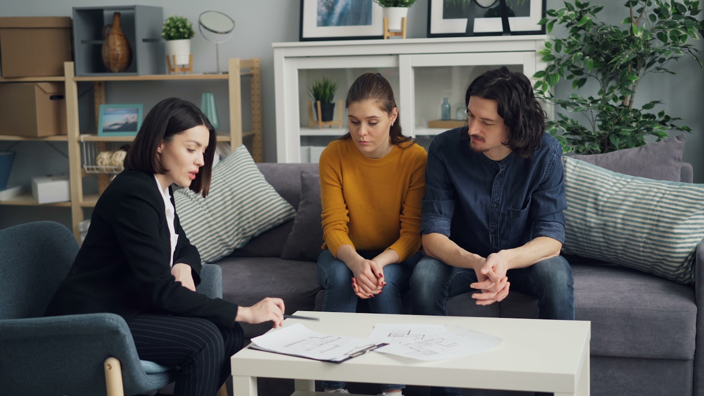 Professional discusses documents with a couple in a modern office.